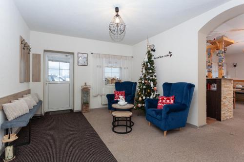 a living room with a christmas tree and blue chairs at Penzión Soňa in Ždiar