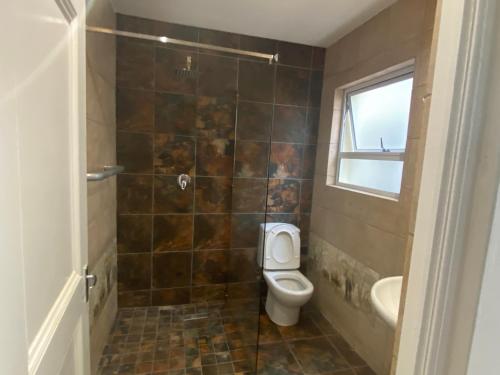 La salle de bains est pourvue de toilettes, d'un lavabo et d'une fenêtre. dans l'établissement Phil's studio, à Midrand