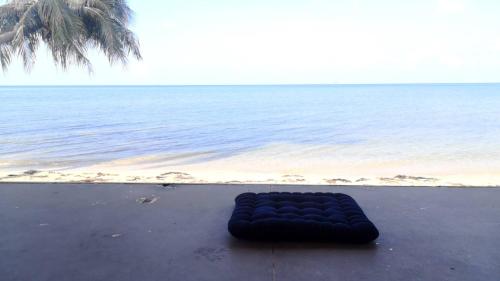 a black beanbag laying on the beach next to the ocean at Jayden Villas in Hinkong