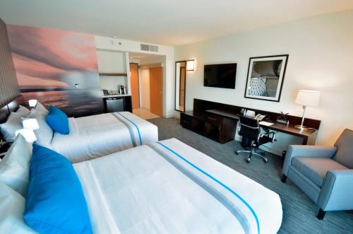 Habitación de hotel con 2 camas y escritorio en The Grand Winnipeg Airport Hotel by Lakeview, en Winnipeg