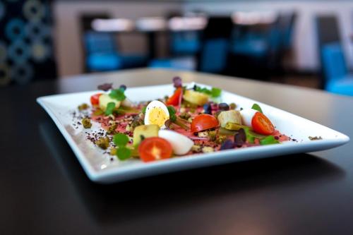 a white plate with a salad on a table at The Grand Winnipeg Airport Hotel by Lakeview in Winnipeg