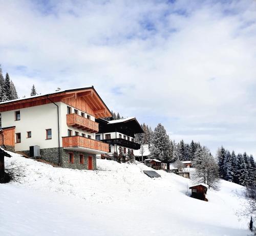 budynek na pokrytym śniegiem wzgórzu z drzewami w obiekcie Ferienhaus Weitblick w mieście Flachau