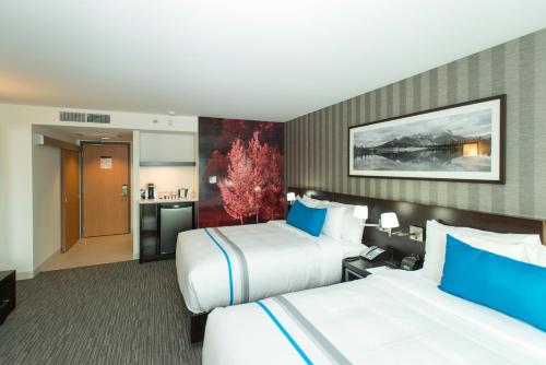 a hotel room with two beds and a kitchen at The Grand Winnipeg Airport Hotel by Lakeview in Winnipeg