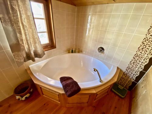 a bath tub in a bathroom with a window at Le Mélézin Bleu in Morgins