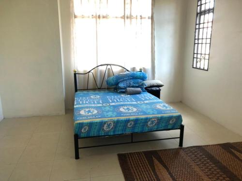 1 dormitorio con 1 cama con manta azul y ventana en Homestay Chik Da en Alor Setar