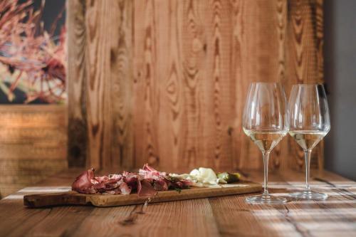 two wine glasses and a plate of food on a table at Cesa Edelweiss Living & Spa in Campitello di Fassa