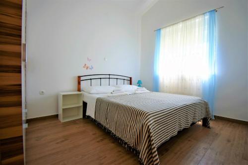 a bedroom with a bed with a striped blanket and a window at Apartmani Bakran in Lopar