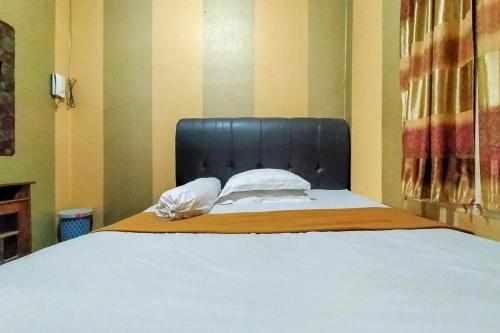 a large bed with a black headboard in a room at Hotel Fikry Toli Toli in Tolitoli