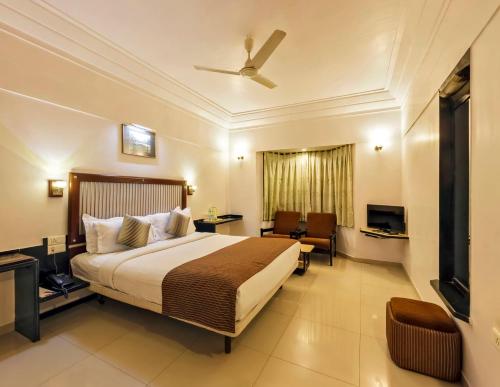 um quarto de hotel com uma cama e uma televisão em Hotel Vrishali Executive em Colhapur