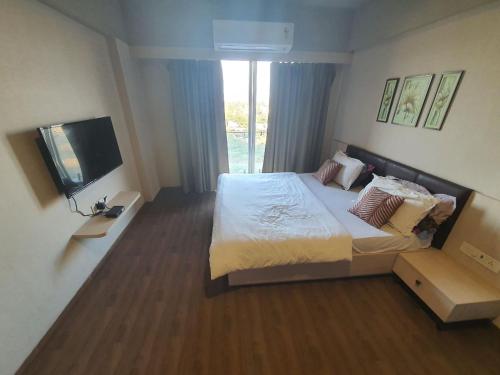 a bedroom with a large bed and a television at Weekend Address Managed By P.C Homes in Surat