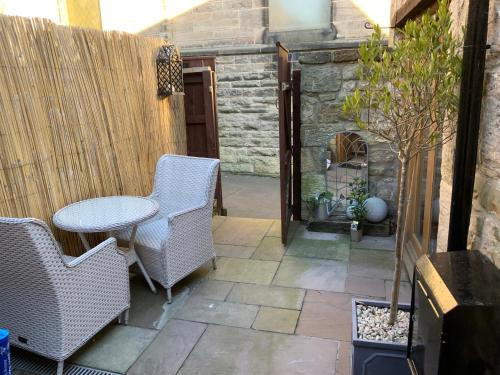 a small patio with a table and chairs and a fence at Chater Cottage Rothbury in Rothbury