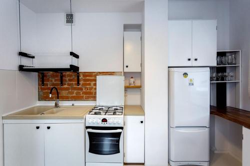 eine weiße Küche mit einem Herd und einem Kühlschrank in der Unterkunft APARTAMENT 16 in Zamość