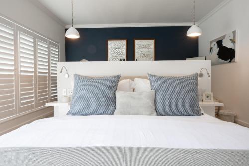 a white bed with blue pillows in a bedroom at Long Story Guest House in Plettenberg Bay
