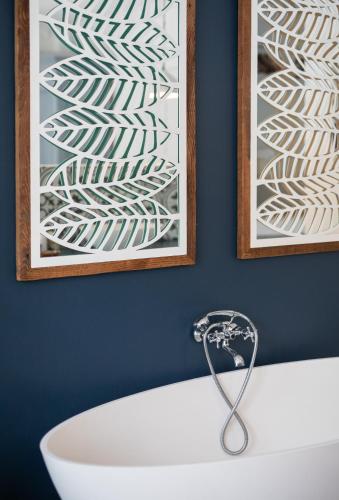 a bathroom with a bath tub and a picture on the wall at Long Story Guest House in Plettenberg Bay