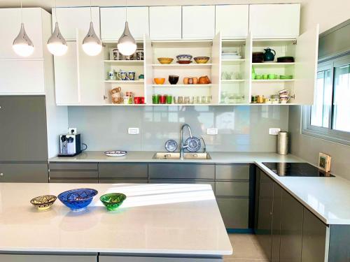 a kitchen with white cabinets and blue bowls on a counter at Beach Apartments in Haifa