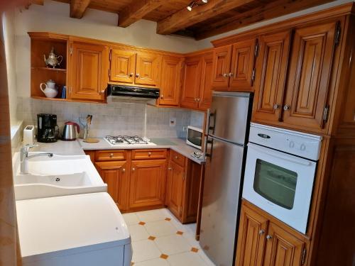 a kitchen with wooden cabinets and a white refrigerator at Logis de Flamenac in Pranzac