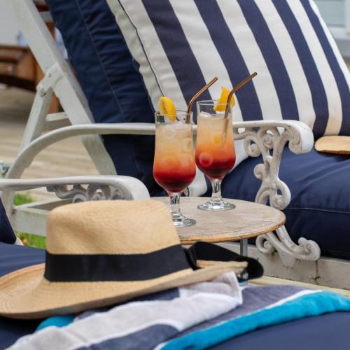 two cocktails sitting on a table with a hat at Long Story Guest House in Plettenberg Bay
