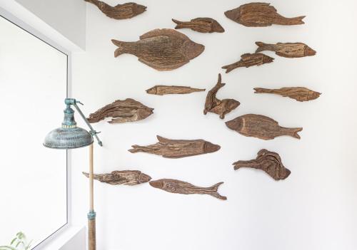a room with a wall covered in wooden fish skeletons at Long Story Guest House in Plettenberg Bay