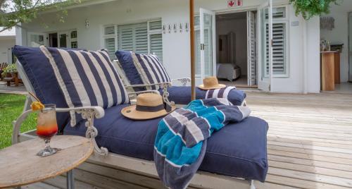 a blue couch with a hat sitting on a patio at Long Story Guest House in Plettenberg Bay