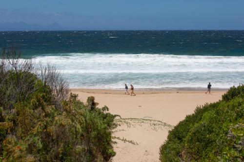 a group of people walking on the beach at Long Story Guest House in Plettenberg Bay