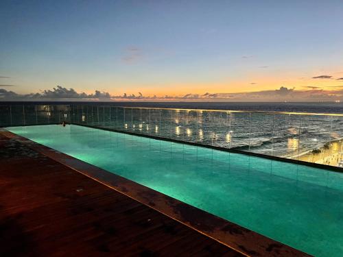 una piscina con el océano en el fondo en Expresso 2222 Charme, en Salvador