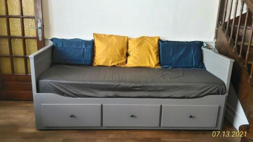 a bed with two blue and yellow pillows on it at Le gite du Mont in Val Couesnon