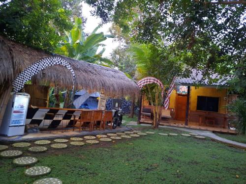 uma casa com telhado de palha e um quintal em Penginapan Sedap Malam em Lovina