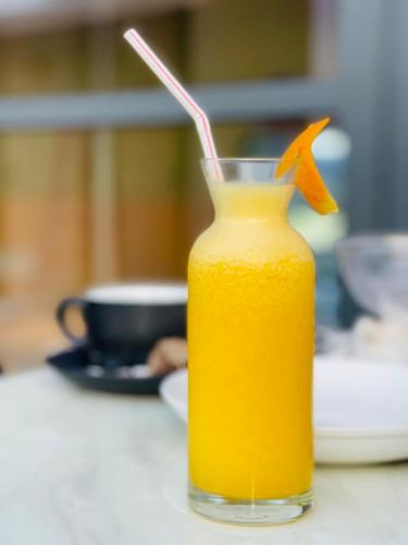 a glass jar of orange juice with a straw at Wish Guesthouse in Huraa