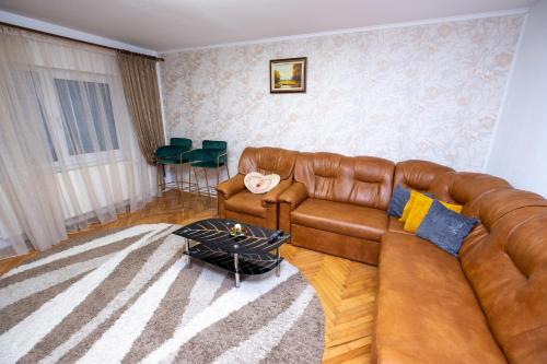 a living room with a brown leather couch and a table at Stella's cozy home in Baloteşti