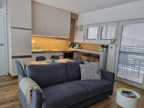 a living room with a blue couch and a kitchen at Apartmán Nad Arénou NMNM in Nové Město na Moravě