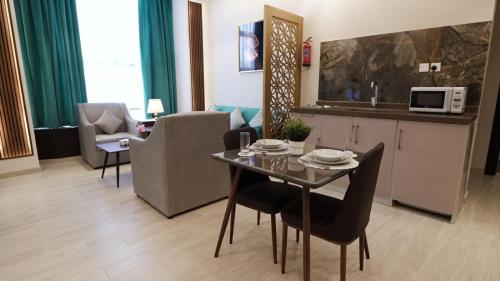 ein Wohnzimmer mit einem Tisch und Stühlen sowie eine Küche in der Unterkunft المنار للوحدات الفندقية in Dschidda