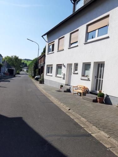 an empty street next to a white building with a bench at Ferienwohnung Schacht in Longkamp