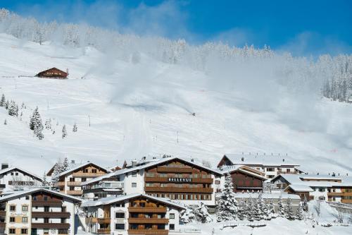 eine Gruppe von Gebäuden auf einem schneebedeckten Berg in der Unterkunft Hotel & Chalet Bellevue in Lech am Arlberg
