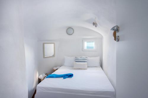 - une chambre avec un lit blanc et une serviette bleue dans l'établissement Kastro Cave House, à Pyrgos