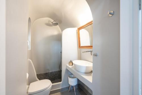 une salle de bain avec des toilettes blanches et un lavabo dans l'établissement Kastro Cave House, à Pyrgos