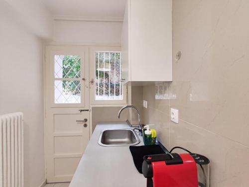 una cucina con un lavandino e una valigia rossa sul bancone di Avli apartment ad Atene