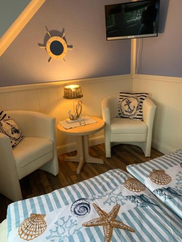 a room with two beds and a chair and a table at Pension Mien Fründt in Baabe