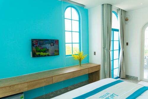 a blue bedroom with a bed and a window at La Casa Boutique Hotel in Vung Tau