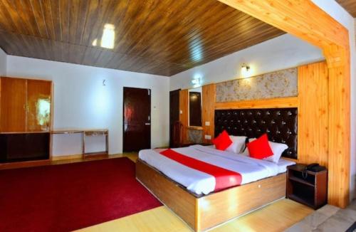 - une chambre avec un grand lit et des oreillers rouges dans l'établissement Hotel River INN, à Manali