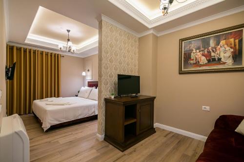 a hotel room with a bed and a television at Legacy Boutique Hotel in Korçë
