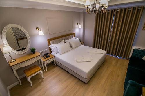 a bedroom with a large white bed and a mirror at Legacy Boutique Hotel in Korçë