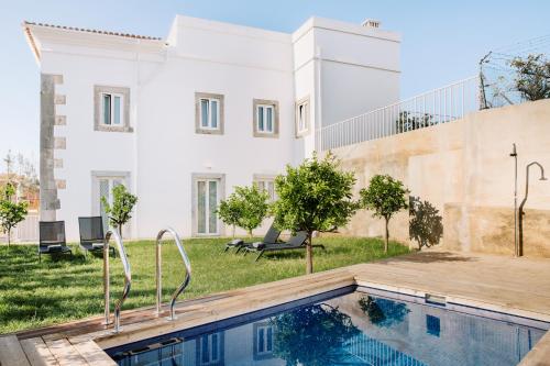 a house with a swimming pool in front of a building at Colégio Charm House in Tavira