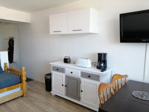 a room with a kitchen with a table and a tv at Studio 4 personnes au pied des pistes in Le Corbier