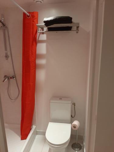 La salle de bains est pourvue de toilettes et d'un rideau de douche rouge. dans l'établissement Palaiseau - proche Orly et Paris, à Palaiseau