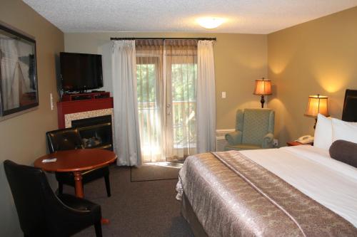a hotel room with a bed and a television and a fireplace at Village Creek Country Inn in Westerose