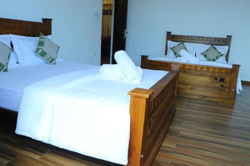 a bedroom with two beds with white sheets and pillows at White House Bungalow Hatton in Hatton