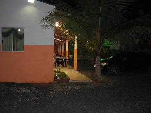a car parked next to a building with a palm tree at Pousada Sol Nascente in Olímpia