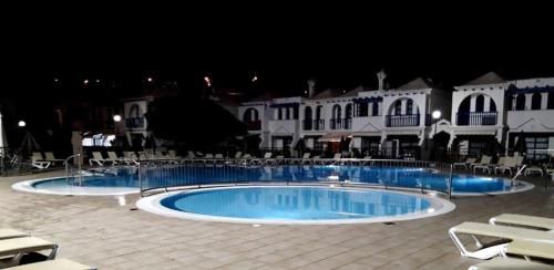 una gran piscina frente a un edificio por la noche en boungalow Mena Playmar en San Bartolomé