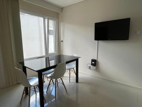 Dpto Moderno - 1 dormitorio, hasta 4 personas في تانديل: غرفة طعام مع طاولة سوداء وكراسي بيضاء