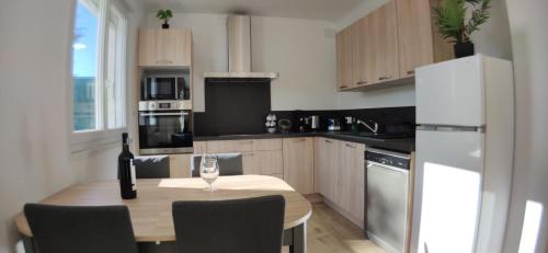 - une cuisine avec une table et un verre de vin dans l'établissement Le jardin des pensées, au Boulou